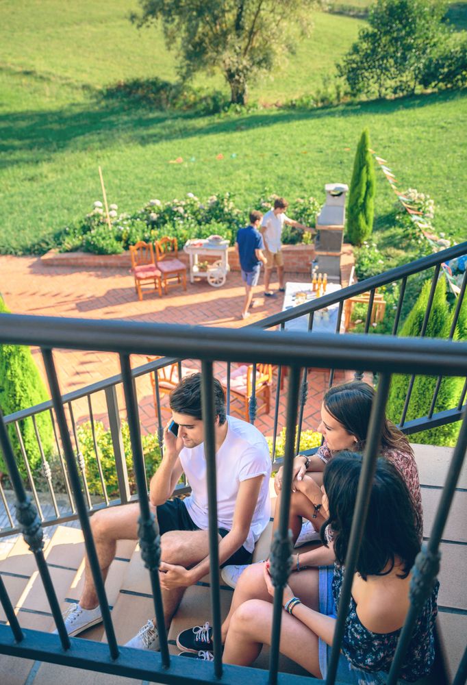 Young man calling by phone sitting on home stairs