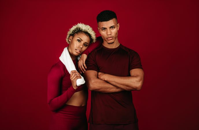 Fit man with arms crossed standing with female athlete