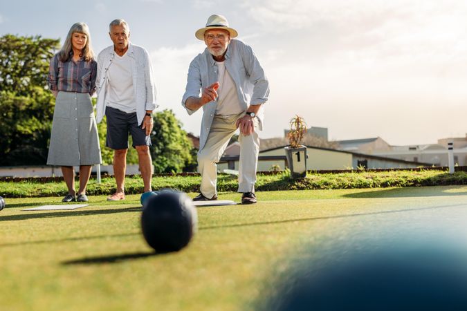 Man in hat throwing a boules while his friends look on
