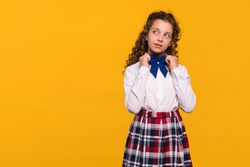 Girl adjusting blue bowtie, thoughtful expression