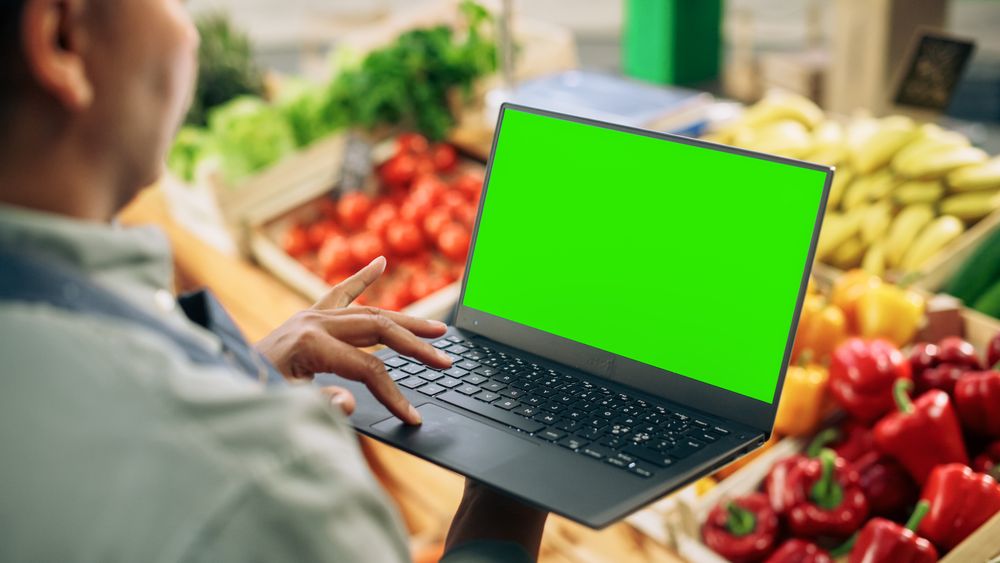 Over the Shoulder Footage of a Street Vendor Using Laptop, Communicating with Sustainable Fruit and Vegetable Supplier