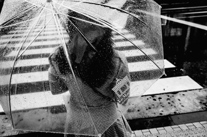 Grayscale photo of woman under transparent umbrella