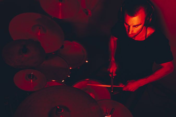 Man with drumsticks playing on drums in redness
