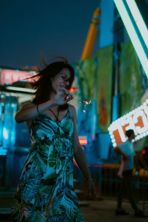 Woman in amusement park with sparkler
