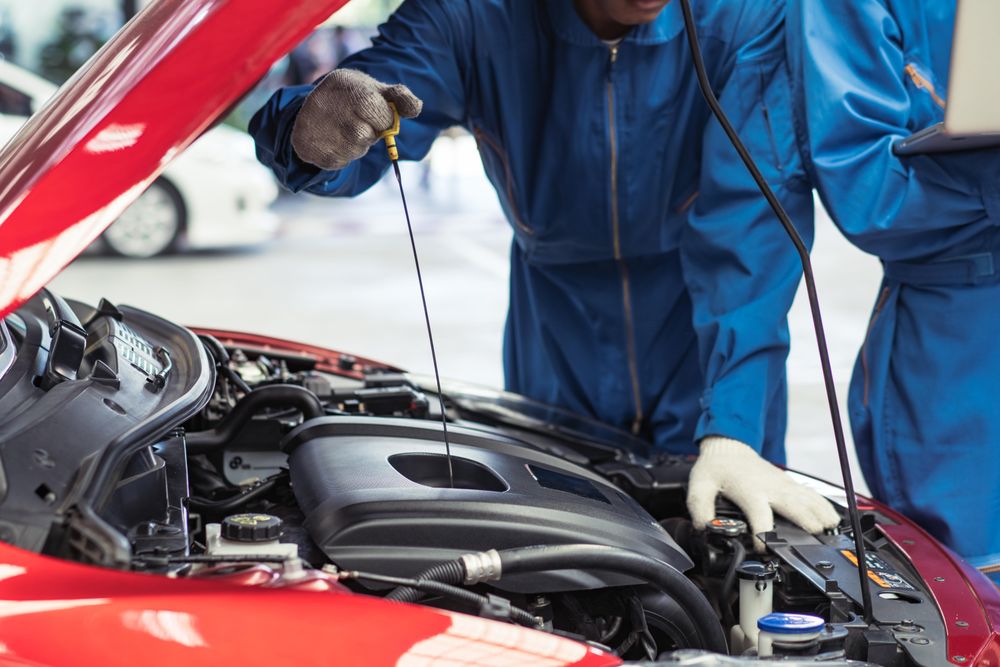 Automobile mechanic checking oil level in the car engine
