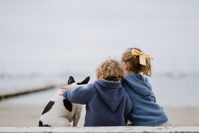 Kids hugging dog on beach