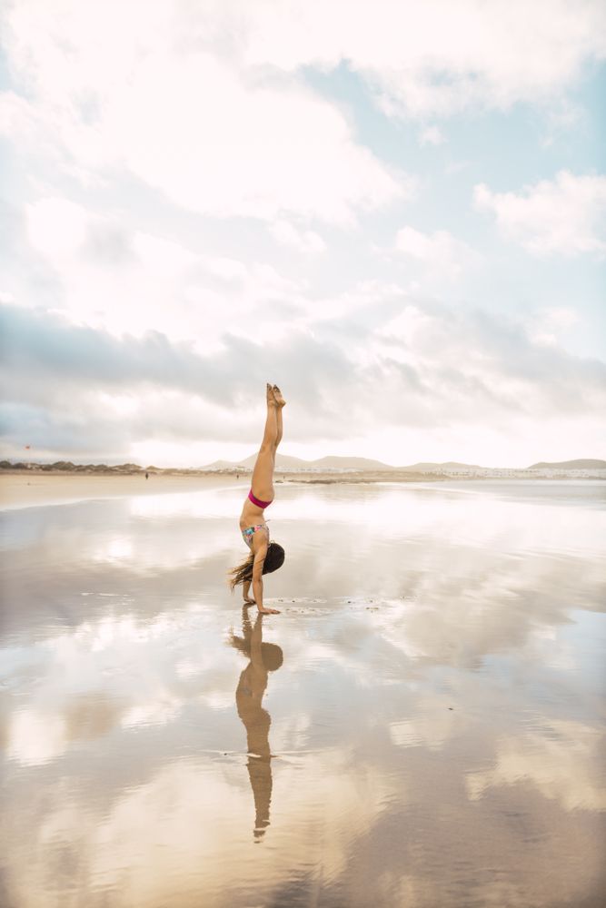 Woman doing handstand near sea