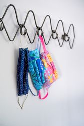 Three colorful masks hang on a coat rack