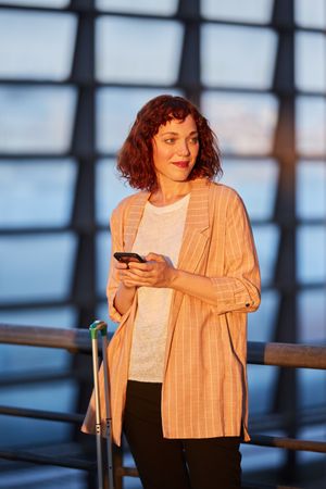 Smiling young woman browsing on phone at station