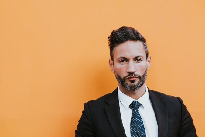 Adult stylish man in costume near orange wall