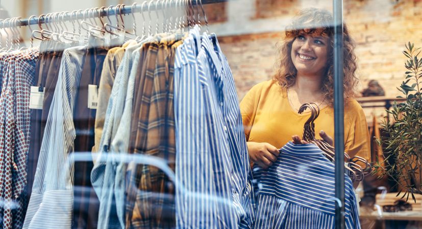 Shop owner adding new clothing to display rack