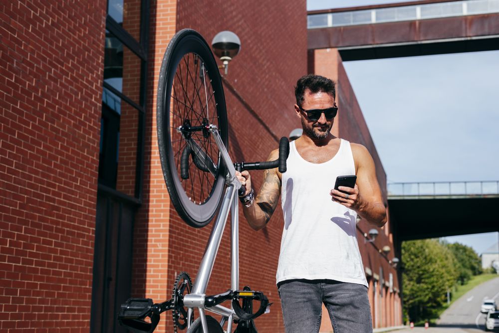Sportive man with bicycle using phone