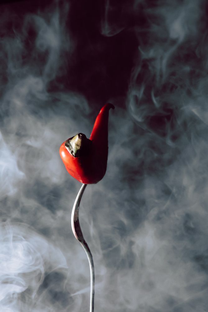 red chili pepper in fork on a dark background with smoke