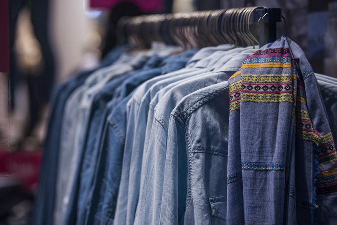 Blue denim jeans shirts hanged on clothes rack in fashion store