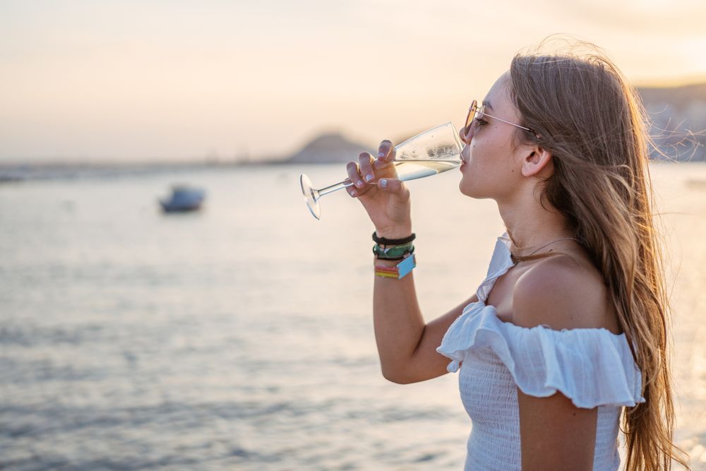 Young woman enjoying wine near sea