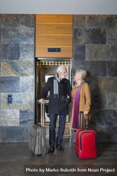 Mature man and woman outside of hotel elevator with luggage 5wd194