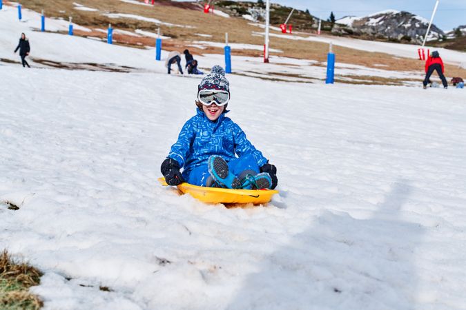 Happy child riding plastic sleigh and smiling
