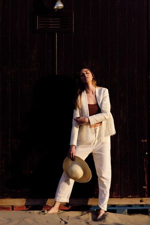 A long hair fashion model with a hat at the beach with a dark background