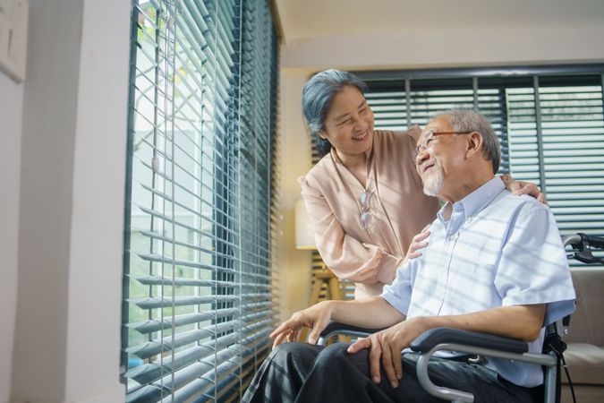Asian woman takes care of mature husband in wheelchair