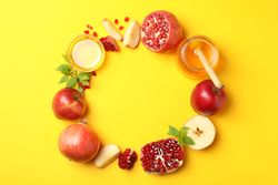 Wreath of apples, pomegranate, honey on yellow background