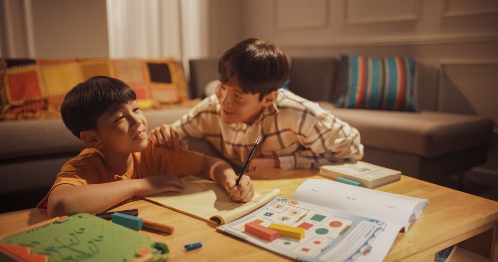 Portrait of the Smart Young Boy Doing Homework with Helpful Father Teaching Him Independent Thinking and Diligence.