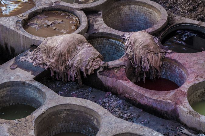 Heaps of dirty textile near containers with colorant liquid