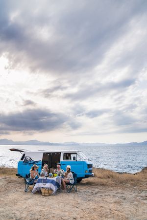 group of friends sitting in chairs next to a minivan
