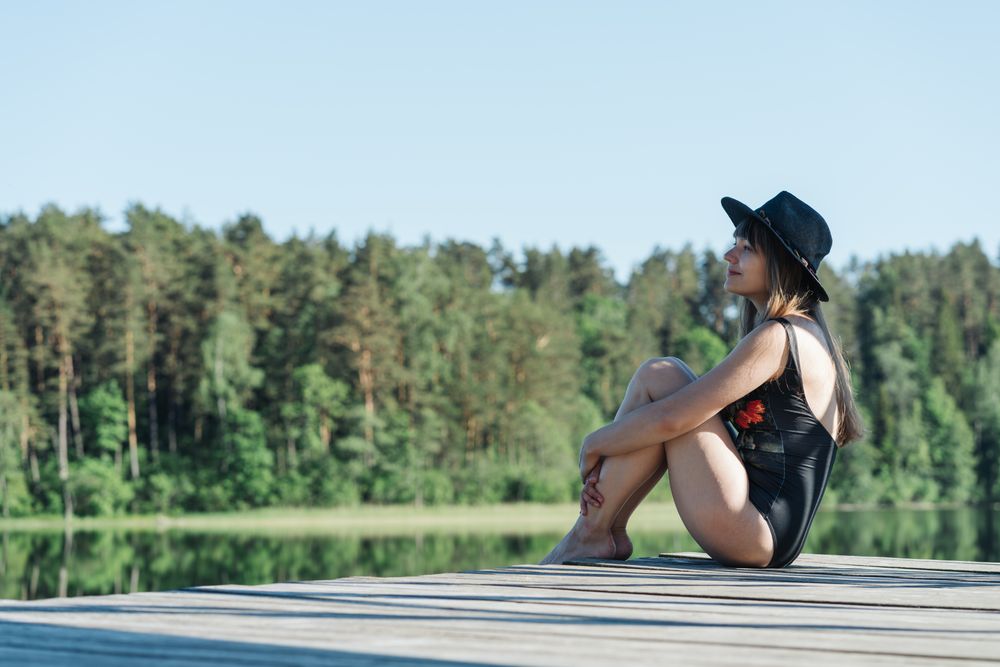 Young female sitting on pier on nature