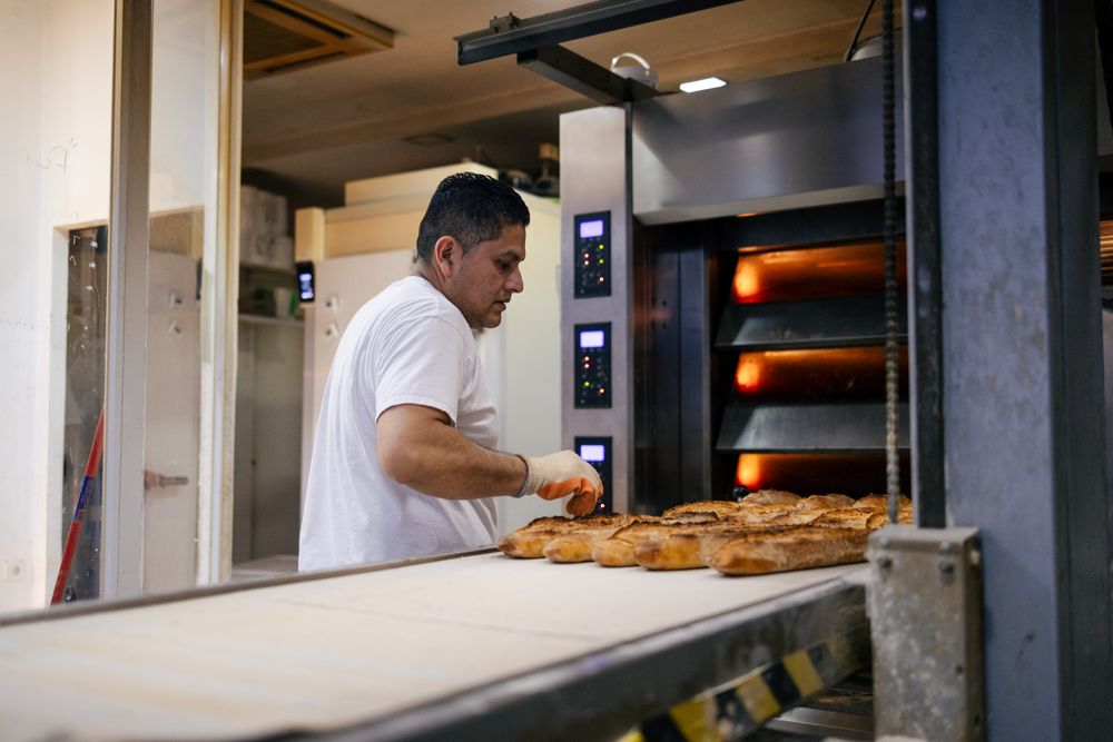 Latino baker taking bread out of the oven
