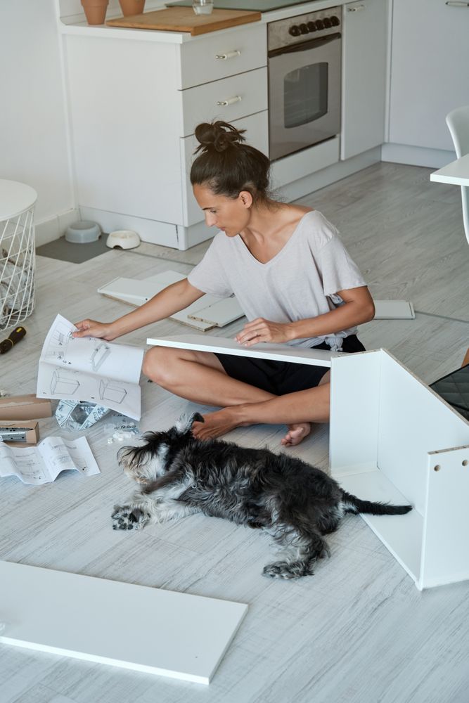 Woman assembling furniture according to instruction in room with