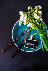 Top view of table setting for spring dinner with flowers on teal plate