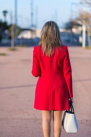 Back of woman in red coat standing on street