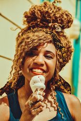 Close up of happy Black female smiling with an ice cream cone in the sun, vertical