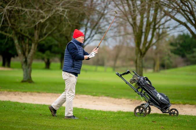 Man swinging club on golf course