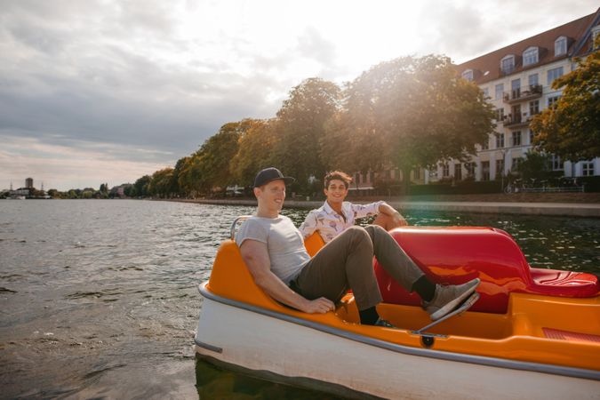 Two young male friends sitting in pedal boat and pedaling