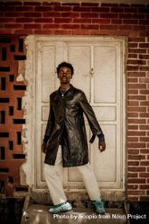 Young man in dark leather coat standing light door 43EOR0