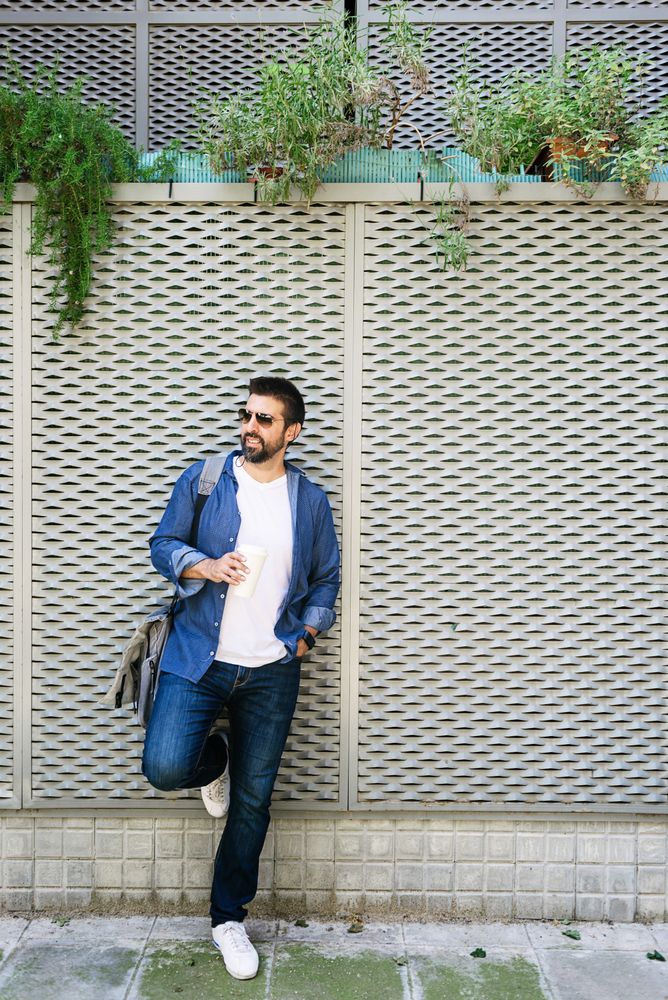 Man in denim leaning on fence outside