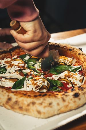 Margherita pizza with basil and tomato served with cold beer on checkered tablecloth