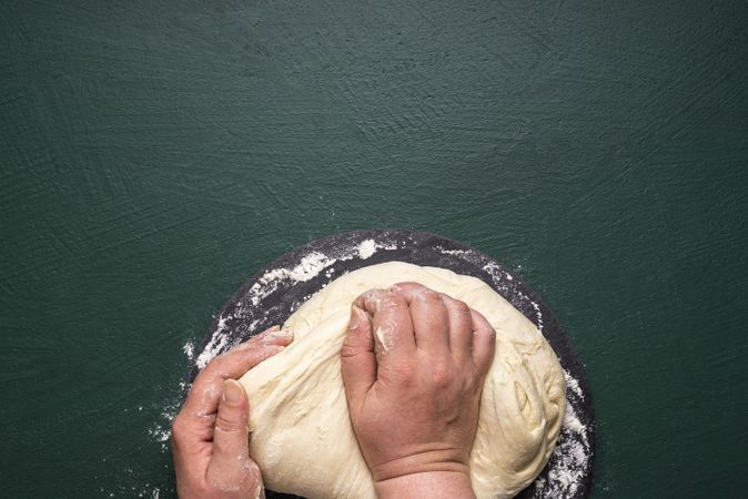 Kneading dough on a green table overhead view