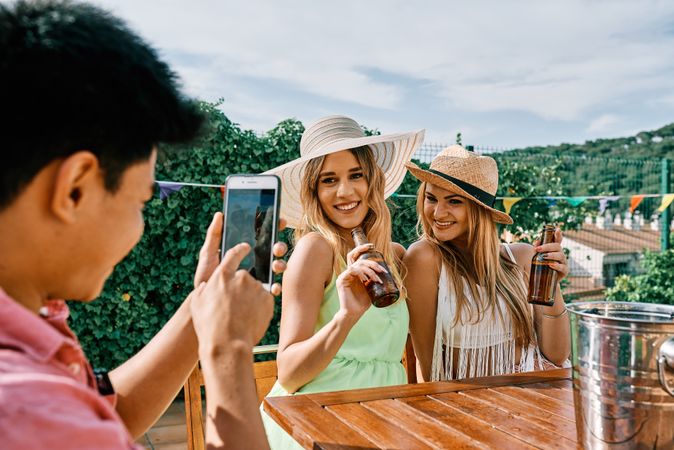 a young man takes a selfie of two blond women