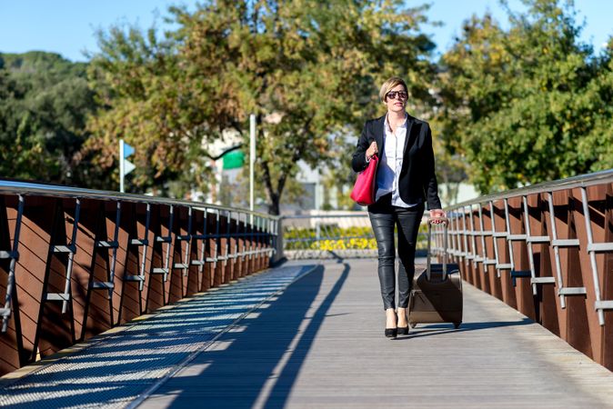 Woman walking across pedestrian bridge with suitcase