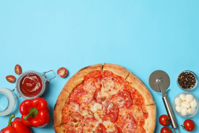 Tasty pizza and ingredients on blue background