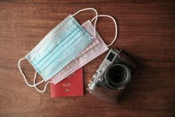 Overhead shot of facemasks, passport and camera on table