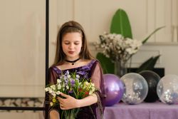 Girl looking at bouquet of flowers at birthday party.