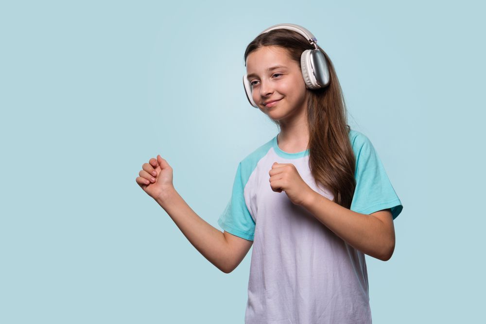 Girl dancing to music with headphones, enjoying the rhythm.