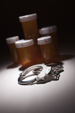 Handcuffs, Medicine Bottle and Pills Under Spot Light