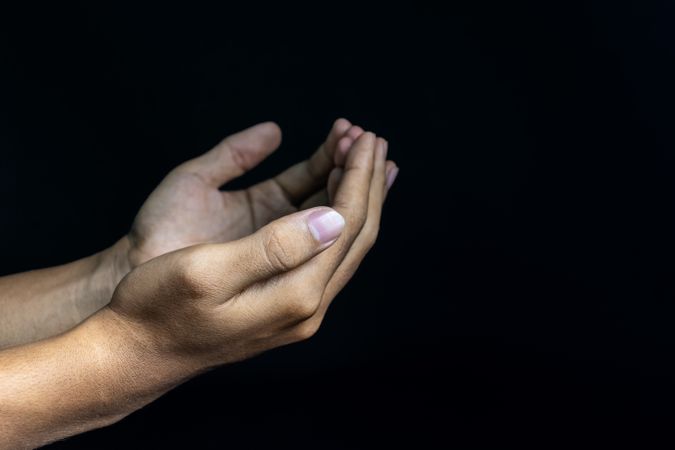 male hands praising or worship gesture isolated on dark background. religion and spirituality concept