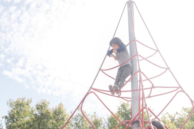 Boy on rope climbing net in sunlight