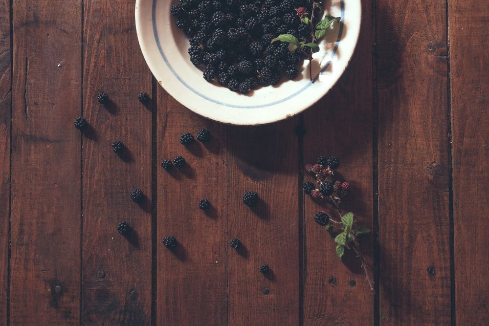Ripe blackberries garnished by leaves in bowl