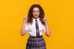 Girl wearing glasses pointing upwards with both hands